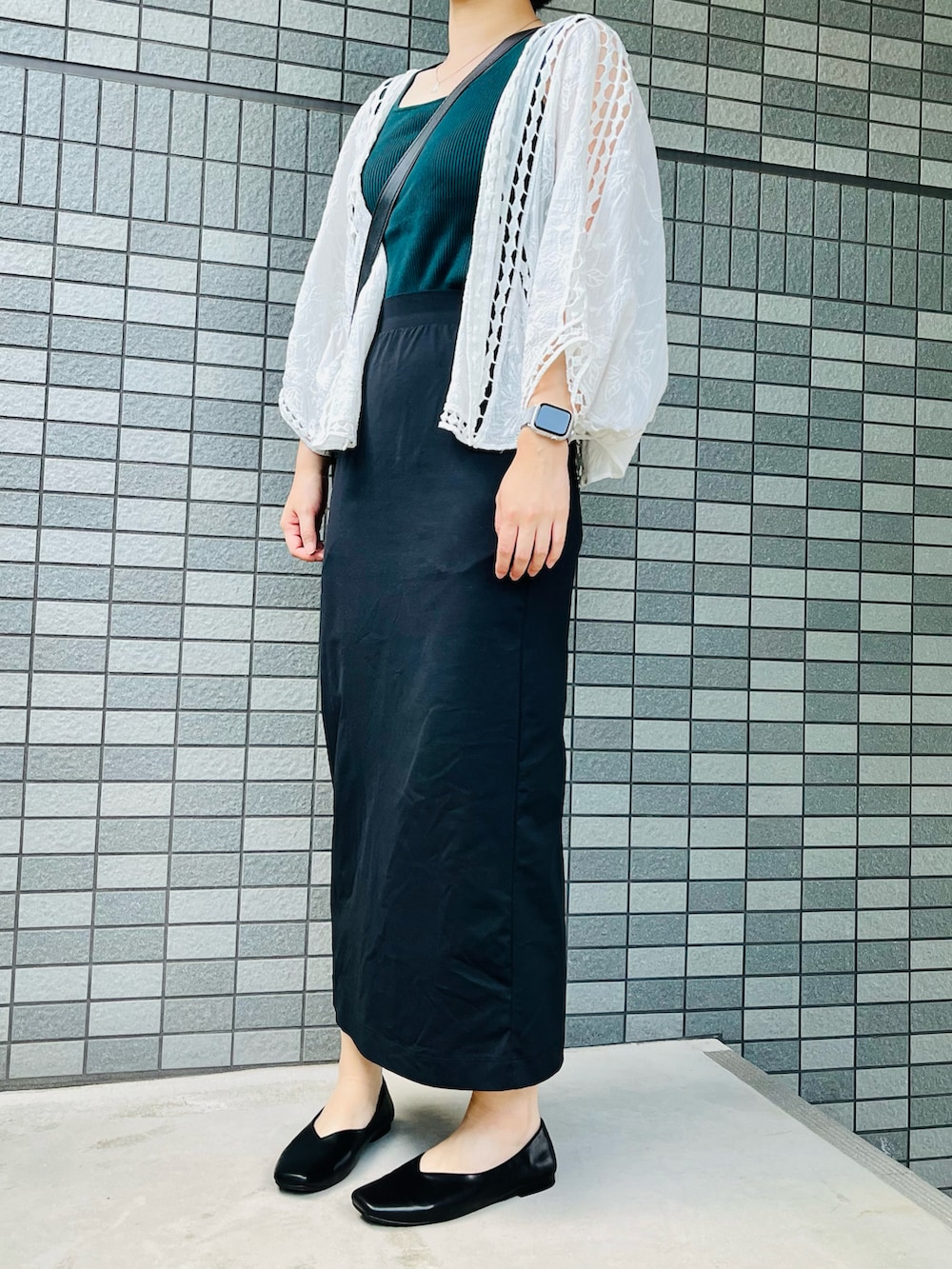 グリーン系のタンクトップ、ブラック系のスカート、ブラック系のパンプスを着用したレディースの夏コーディネートの2枚目の写真