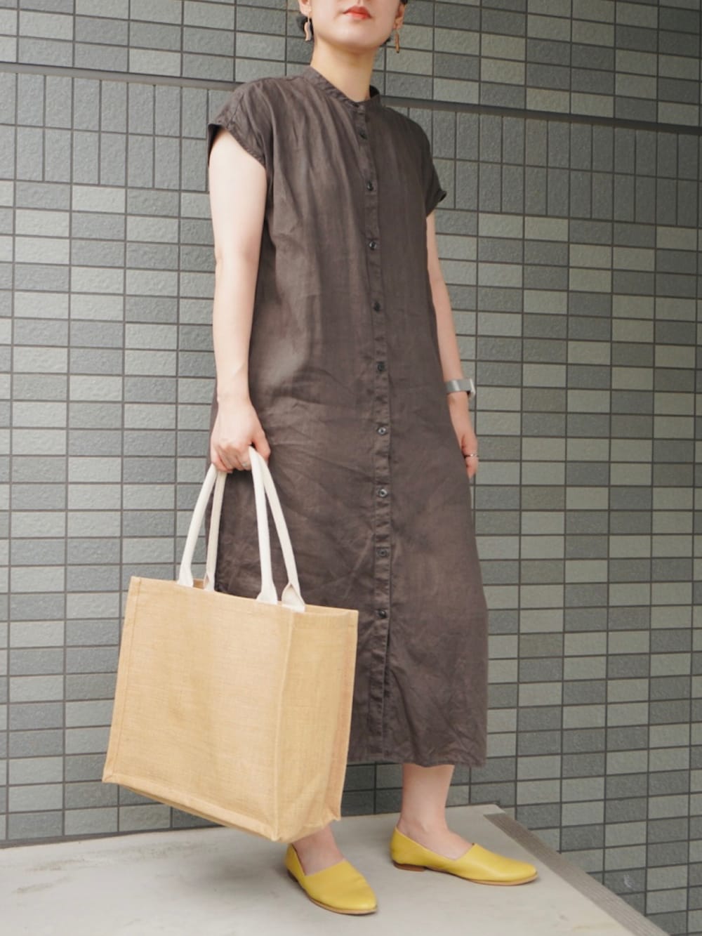 ベージュ系のトートバッグ、イエロー系のパンプス、ブラック系のシャツワンピースを着用したレディースの夏コーディネートの2枚目の写真