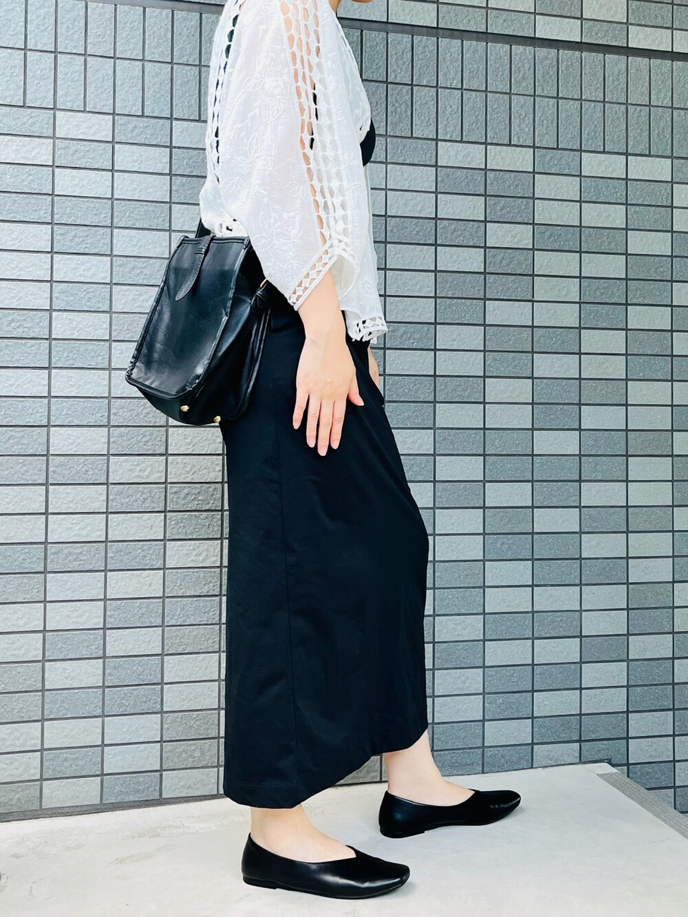 グリーン系のタンクトップ、ブラック系のスカート、ブラック系のパンプスを着用したレディースの夏コーディネートの3枚目の写真