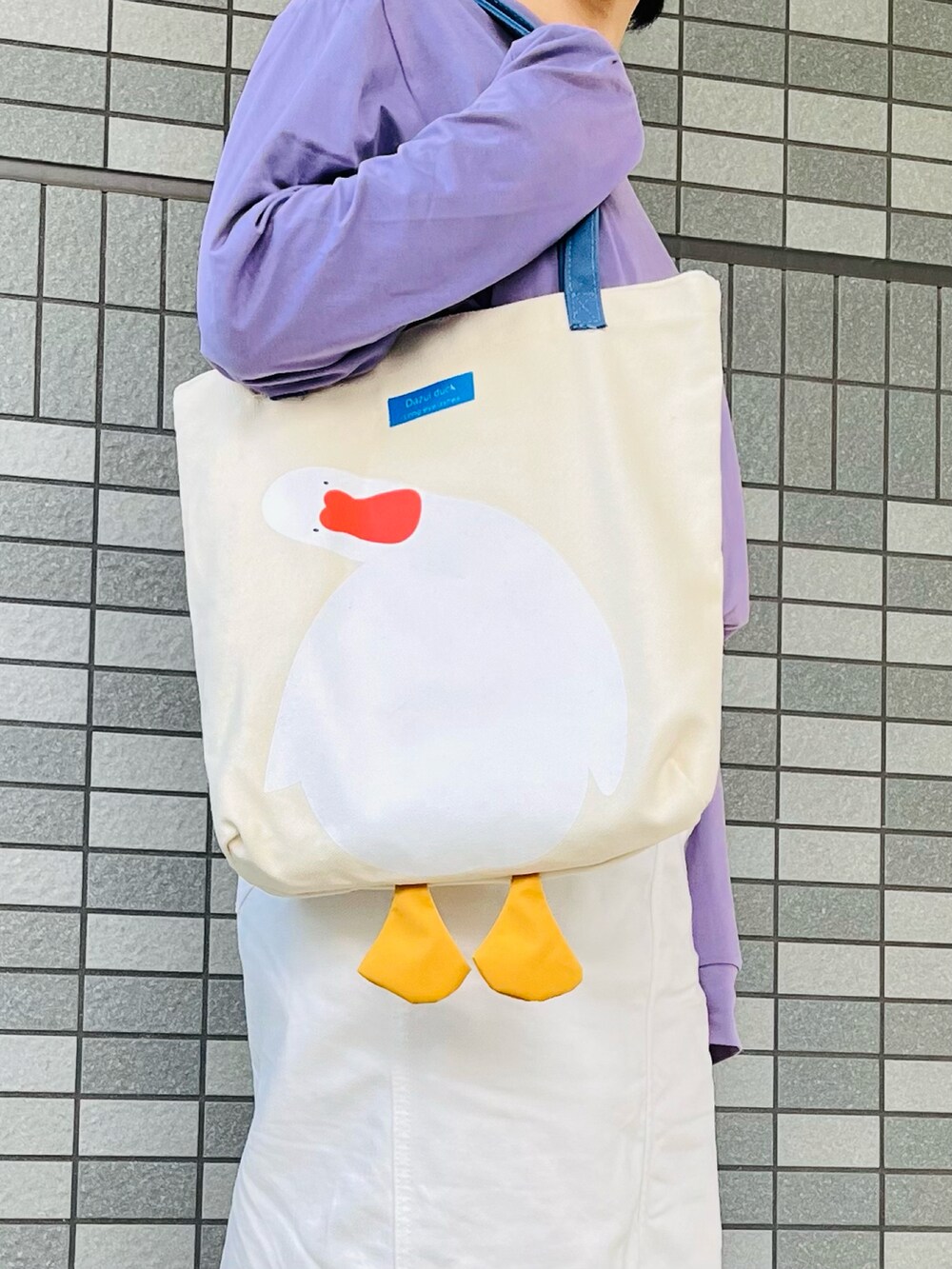 パープル系のTシャツ/カットソー、ホワイト系のデニムスカート、ホワイト系のトートバッグを着用したレディースの夏コーディネートの3枚目の写真