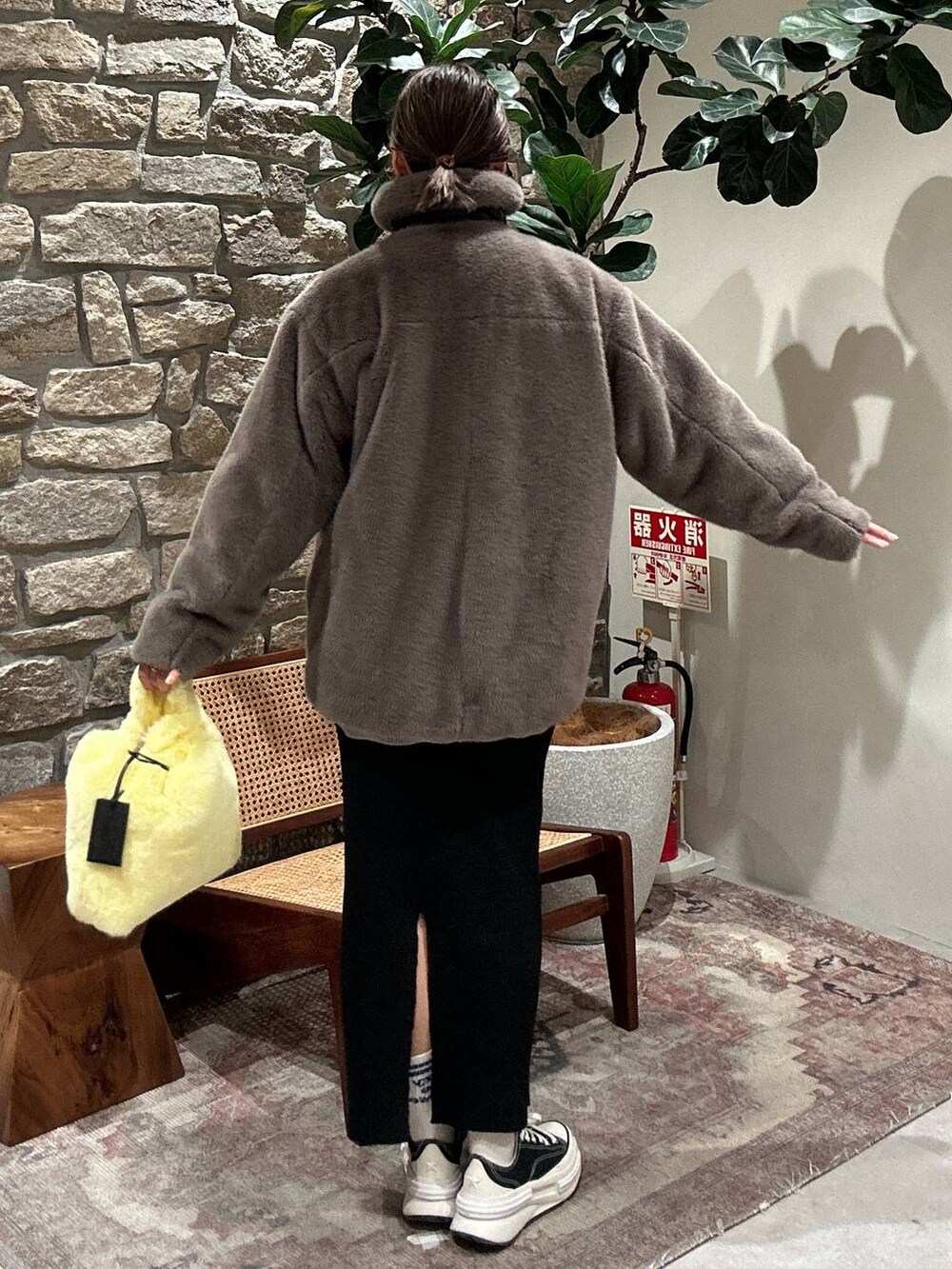 ブラック系のスカート、イエロー系のハンドバッグ、ベージュ系のブルゾンを着用したレディースの秋コーディネートの4枚目の写真