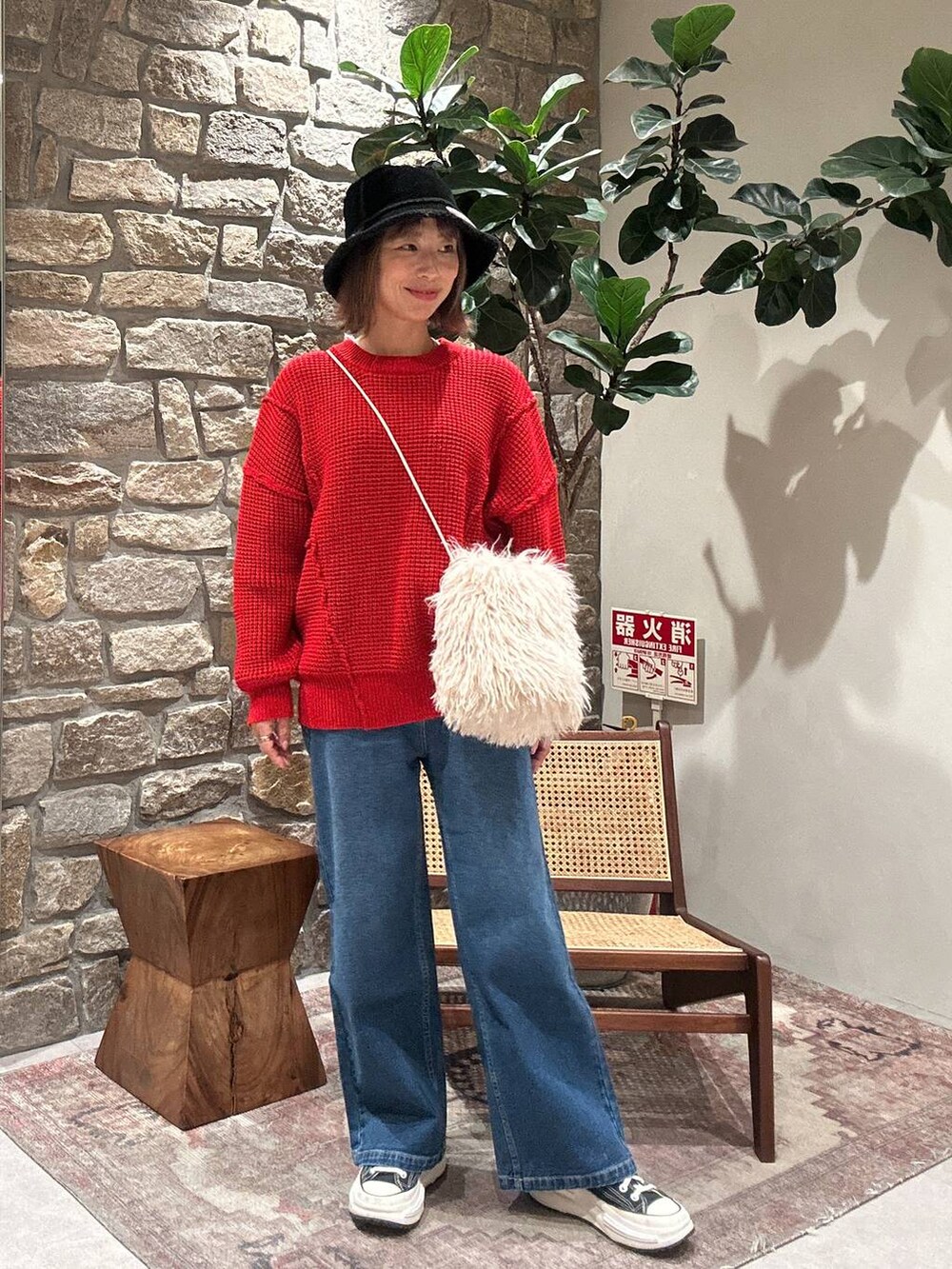 レッド系のニット/セーター、ブルー系のデニムパンツ、ブラック系のハットを着用したレディースの冬コーディネートの3枚目の写真