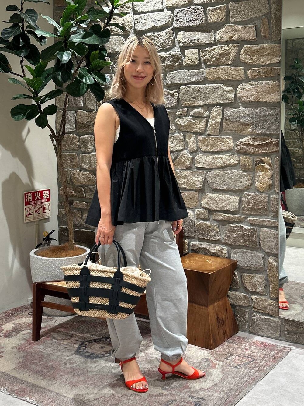 ブラック系のかごバッグ、レッド系のサンダル、グレー系のその他パンツを着用したレディースの夏コーディネートの4枚目の写真