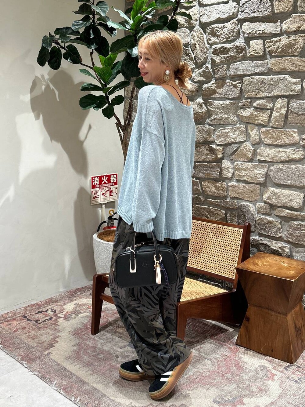 ブラック系のキャミソール、ブラック系のショルダーバッグ、ブルー系のニット/セーターを着用したレディースの春コーディネートの2枚目の写真