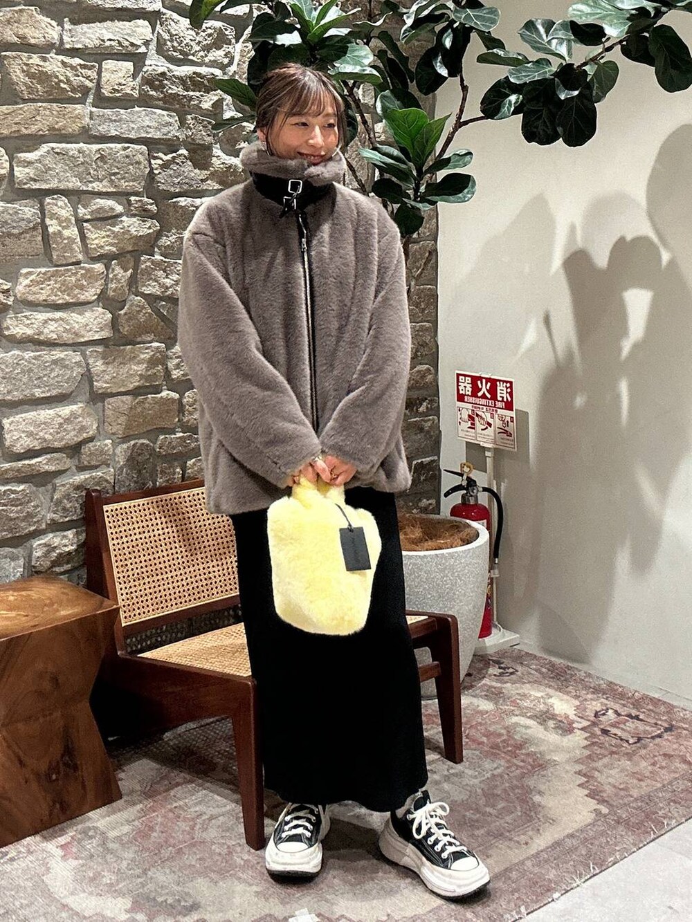 ブラック系のスカート、イエロー系のハンドバッグ、ベージュ系のブルゾンを着用したレディースの秋コーディネートの2枚目の写真