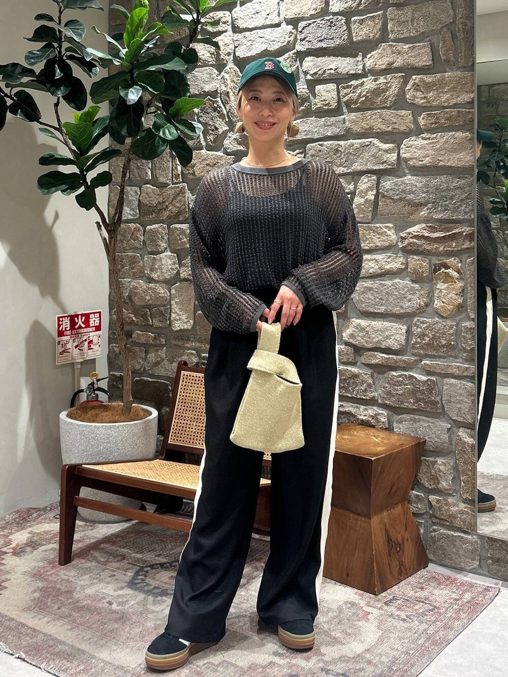 イエロー系のハンドバッグ、グレー系のTシャツ/カットソー、グリーン系のキャップを着用したレディースの春コーディネートの2枚目の写真