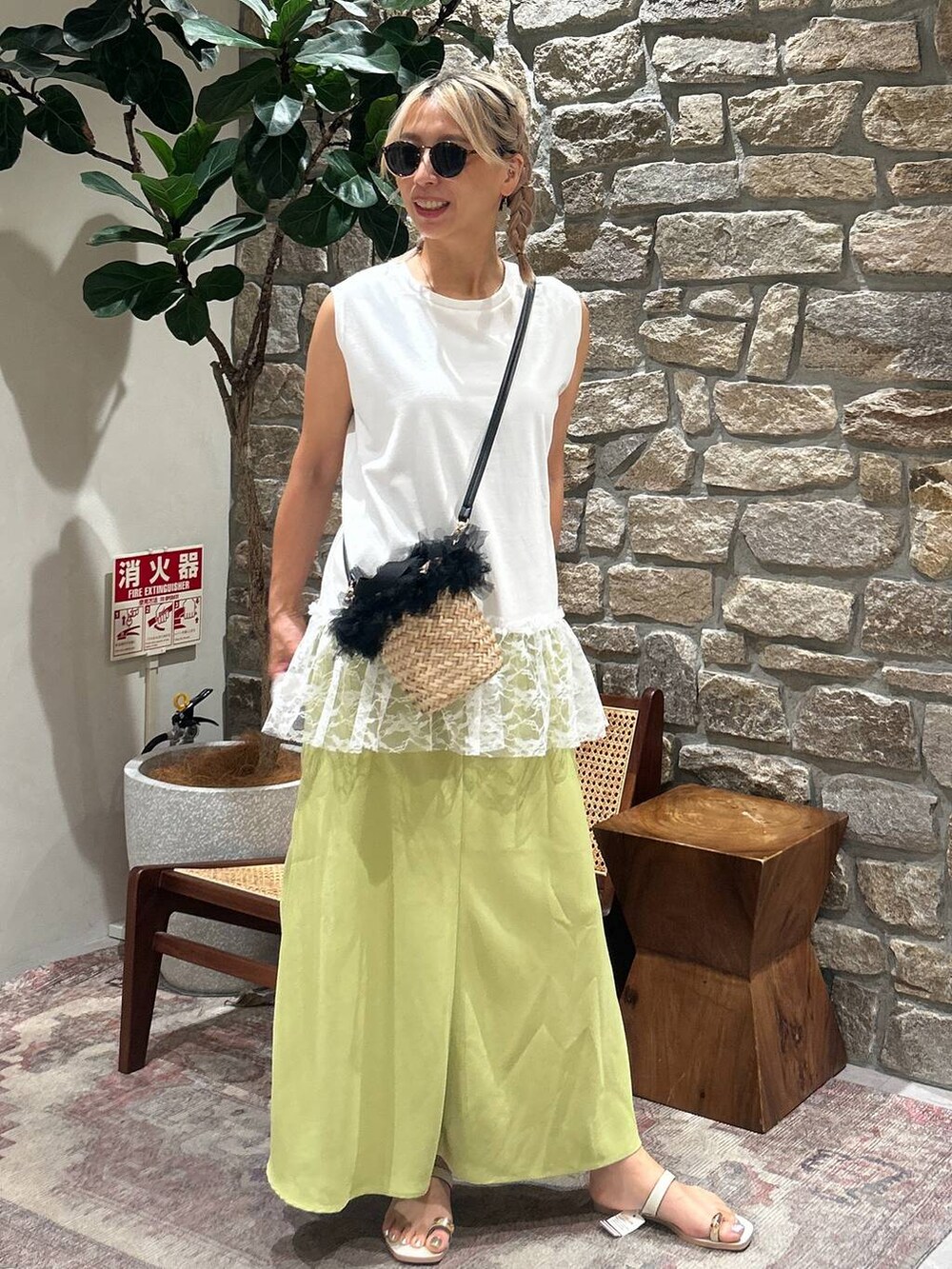 ブラック系のかごバッグ、ホワイト系のサンダル、ホワイト系のTシャツ/カットソーを着用したレディースの夏コーディネートの2枚目の写真