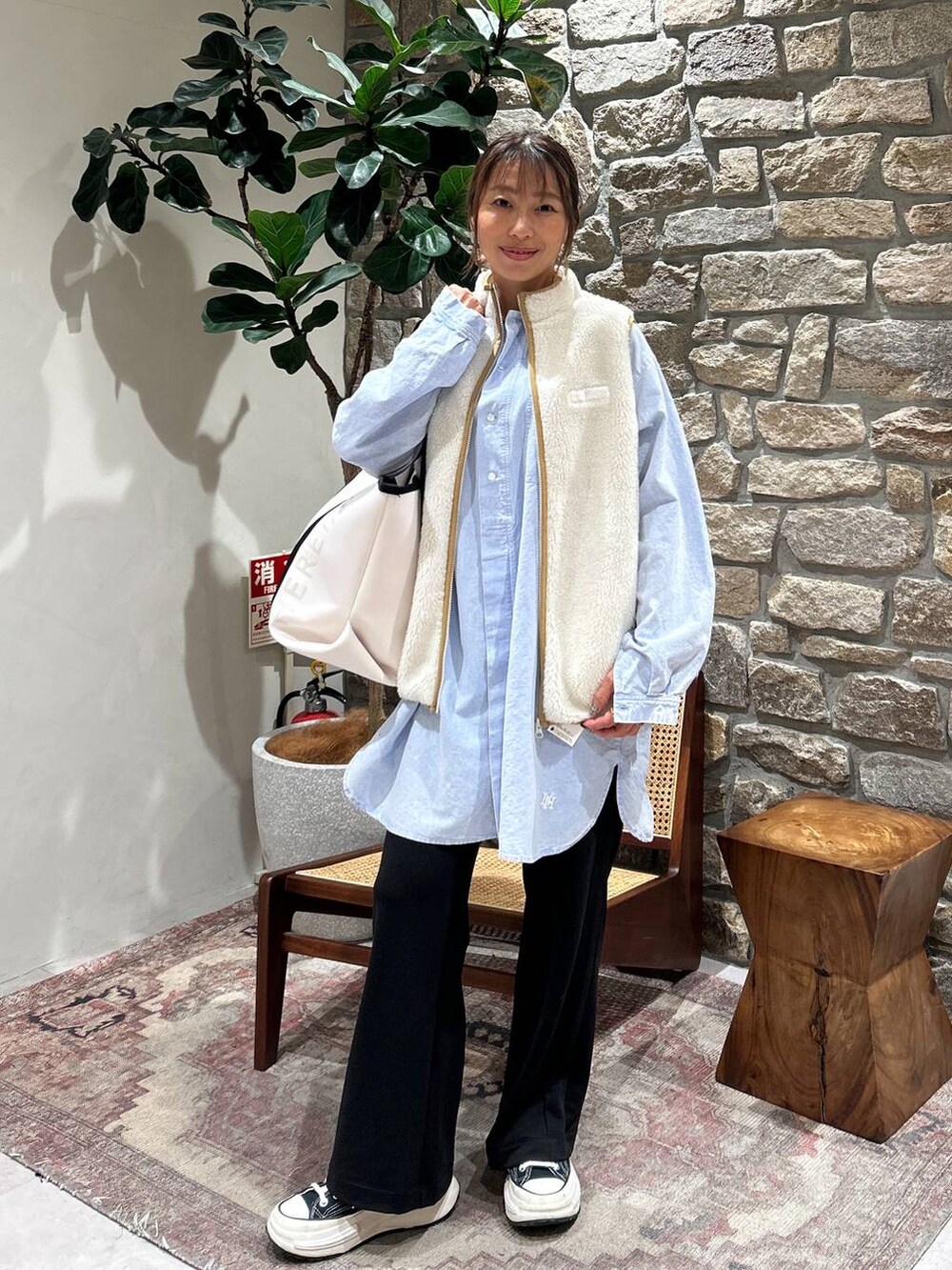 ホワイト系のダウンベスト、ブルー系のシャツ/ブラウス、ベージュ系のトートバッグを着用したレディースの冬コーディネートの3枚目の写真