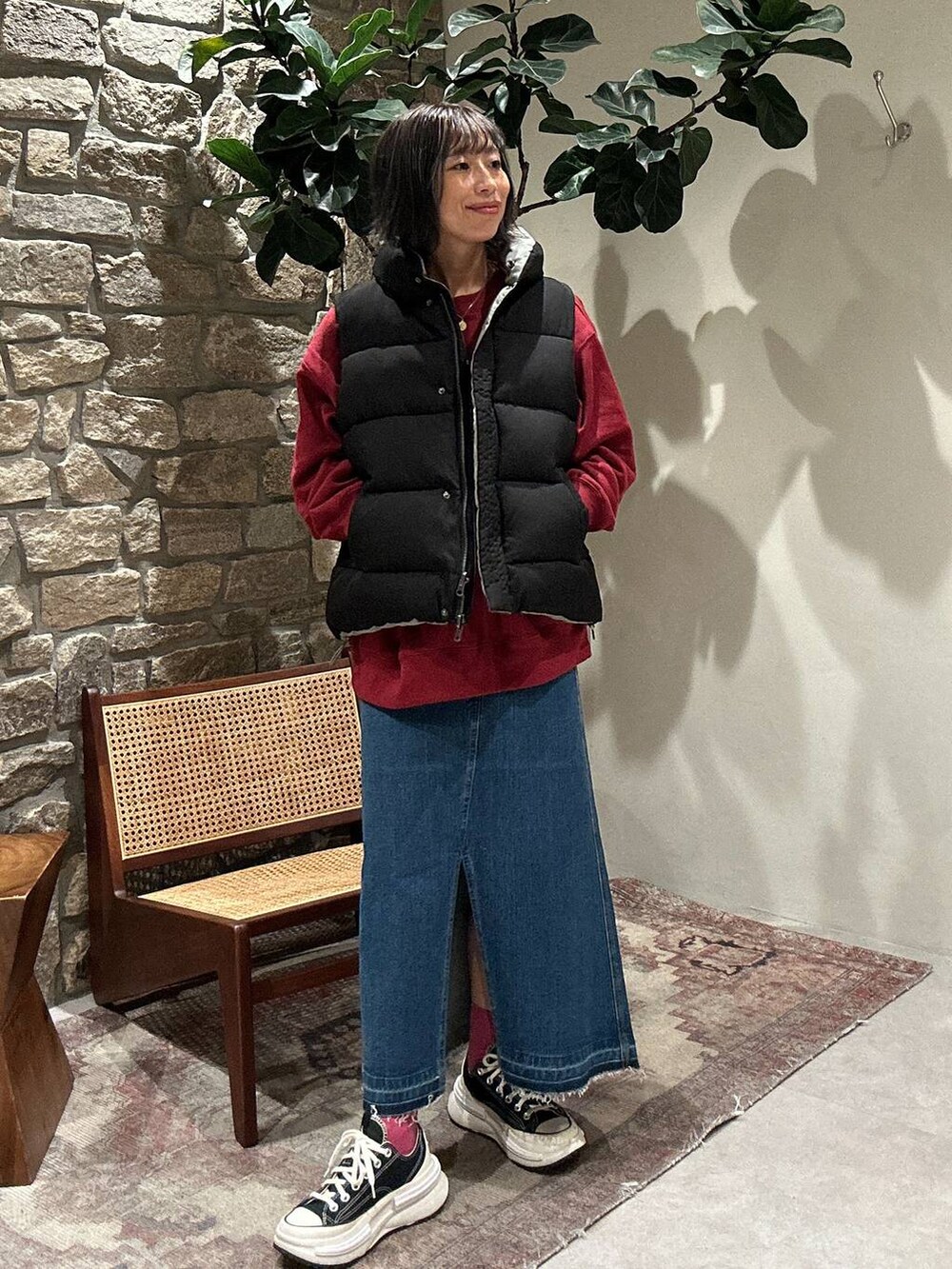 ブルー系のデニムスカート、ブラック系のベスト、レッド系のスウェットを着用したレディースの秋コーディネートの3枚目の写真