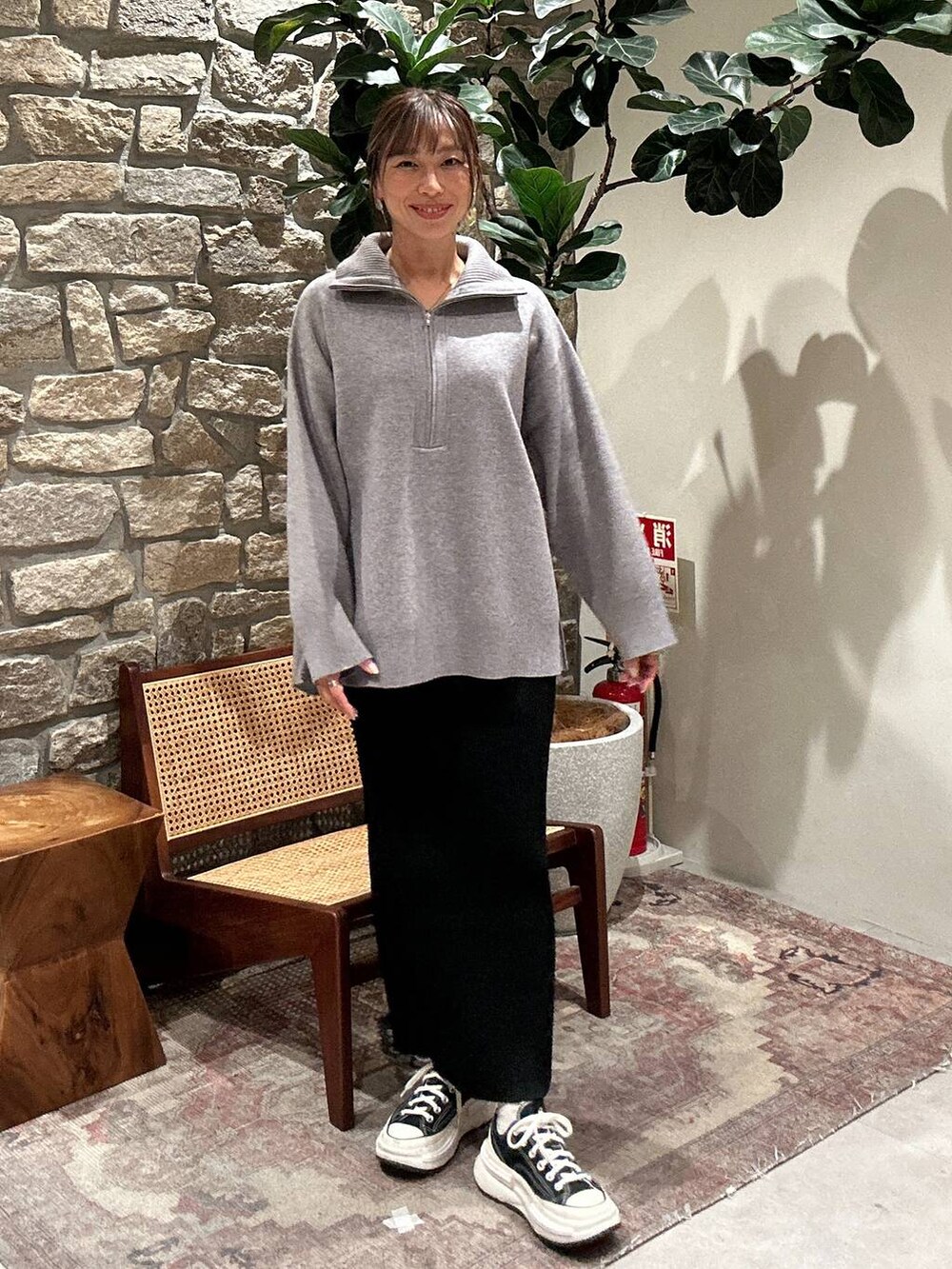 ブラック系のスカート、グレー系のニット/セーターを着用したレディースの秋コーディネートの2枚目の写真