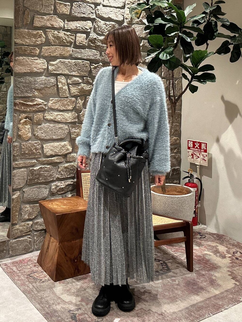 ブラック系のブーツ、シルバー系のスカート、ブラック系のショルダーバッグを着用したレディースの冬コーディネートの2枚目の写真