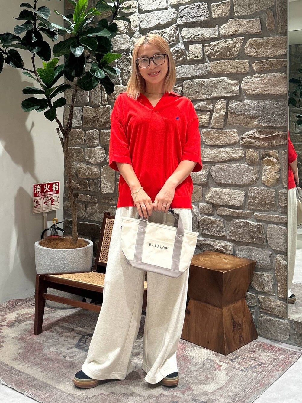 レッド系のニット/セーター、ベージュ系のトートバッグ、ベージュ系のスウェットパンツを着用したレディースの春コーディネートの2枚目の写真