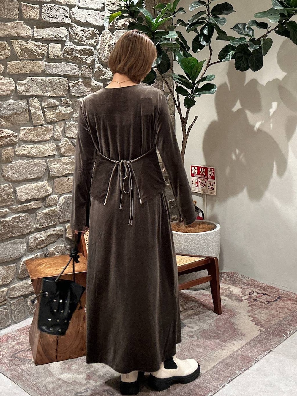 ブラック系のショルダーバッグ、ホワイト系のブーツ、グリーン系のワンピースを着用したレディースの秋コーディネートの2枚目の写真