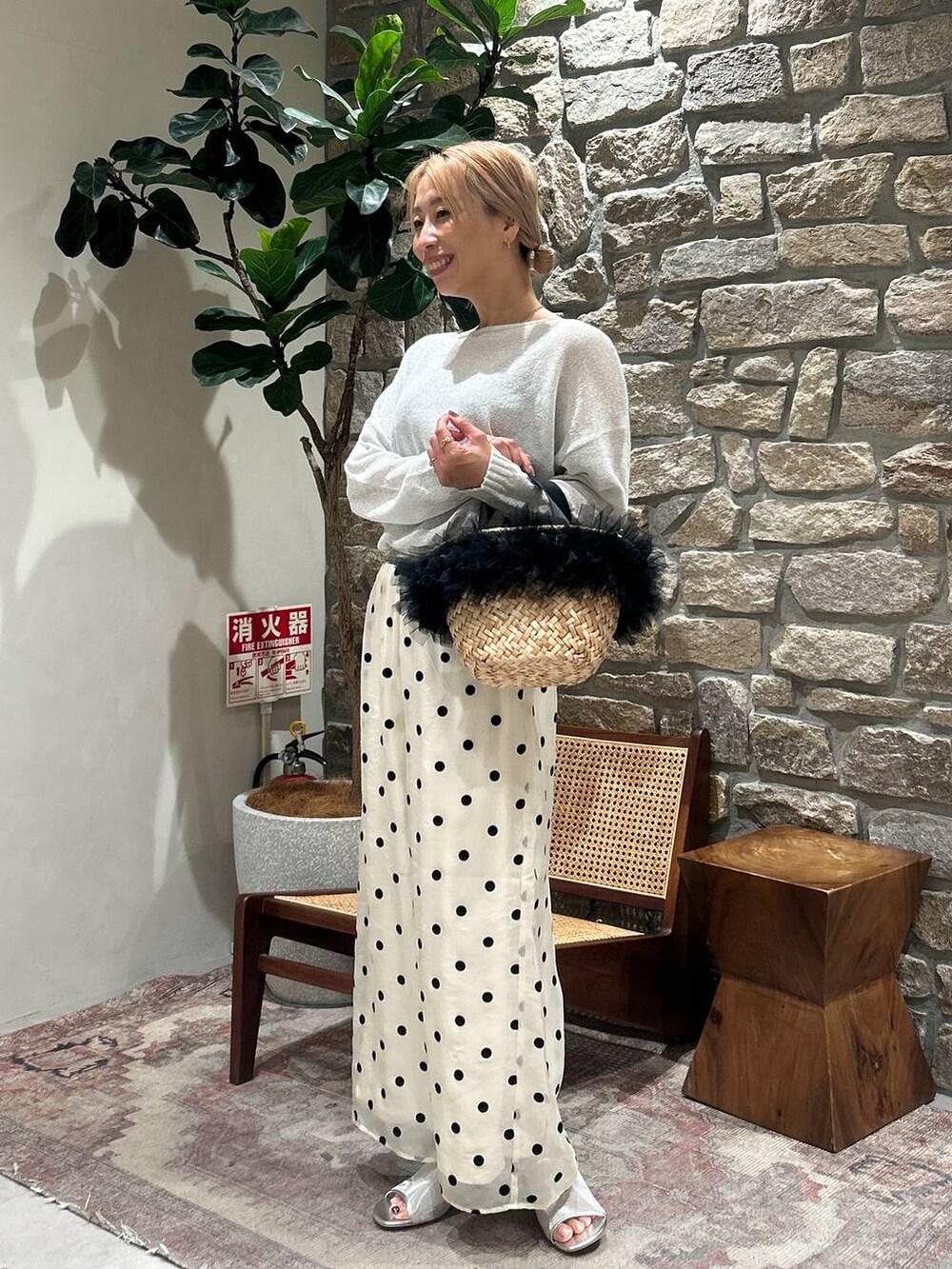 ブラック系のかごバッグ、ホワイト系のTシャツ/カットソー、シルバー系のサンダルを着用したレディースの春コーディネートの2枚目の写真