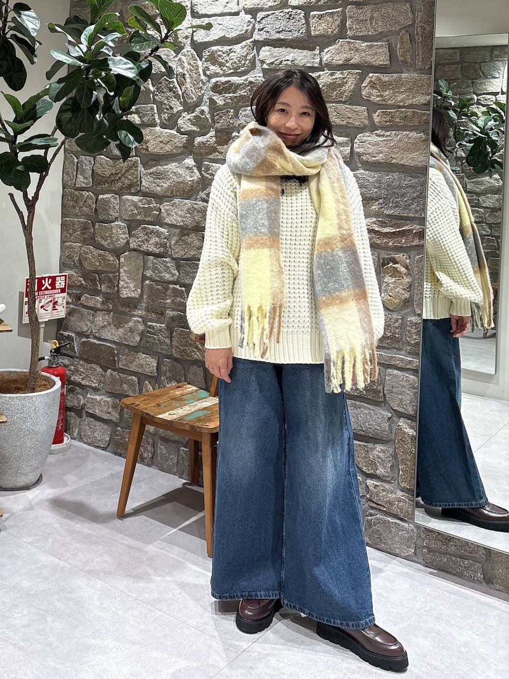 ブラウン系のブーツ、ブルー系のデニムパンツ、イエロー系のマフラーを着用したレディースの冬コーディネートの2枚目の写真