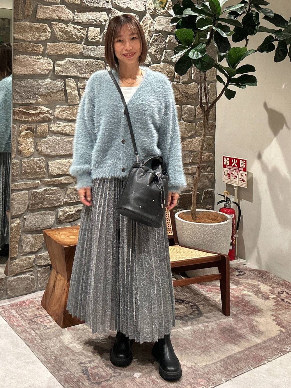 ブラック系のブーツ、シルバー系のスカート、ブラック系のショルダーバッグを着用したレディースの冬コーディネートの3枚目の写真