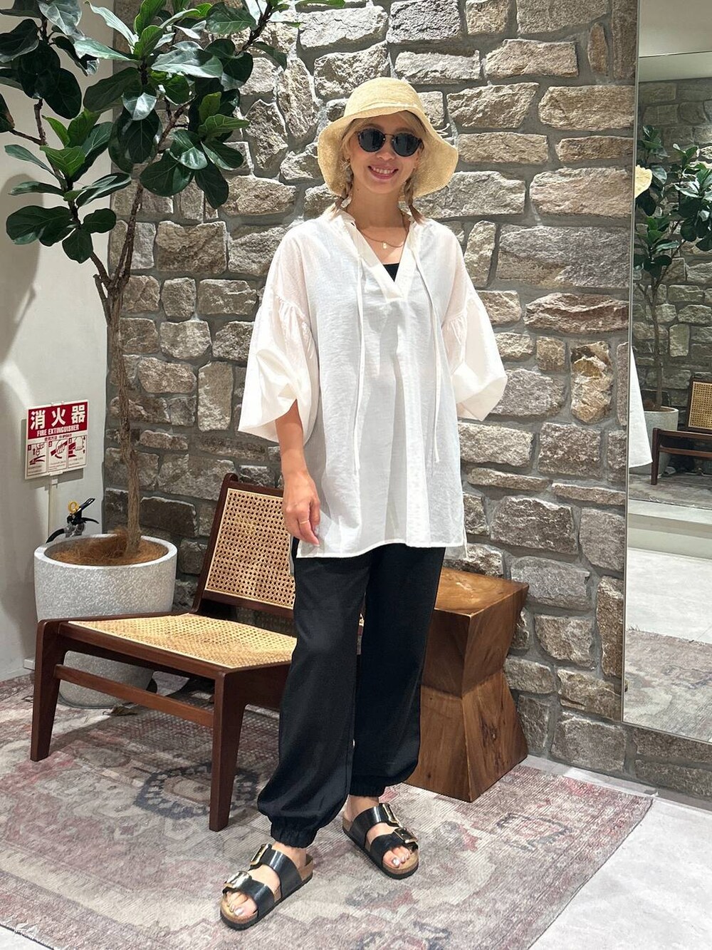 ブラック系のその他パンツ、ホワイト系のチュニック、その他のハットを着用したレディースの夏コーディネートの2枚目の写真