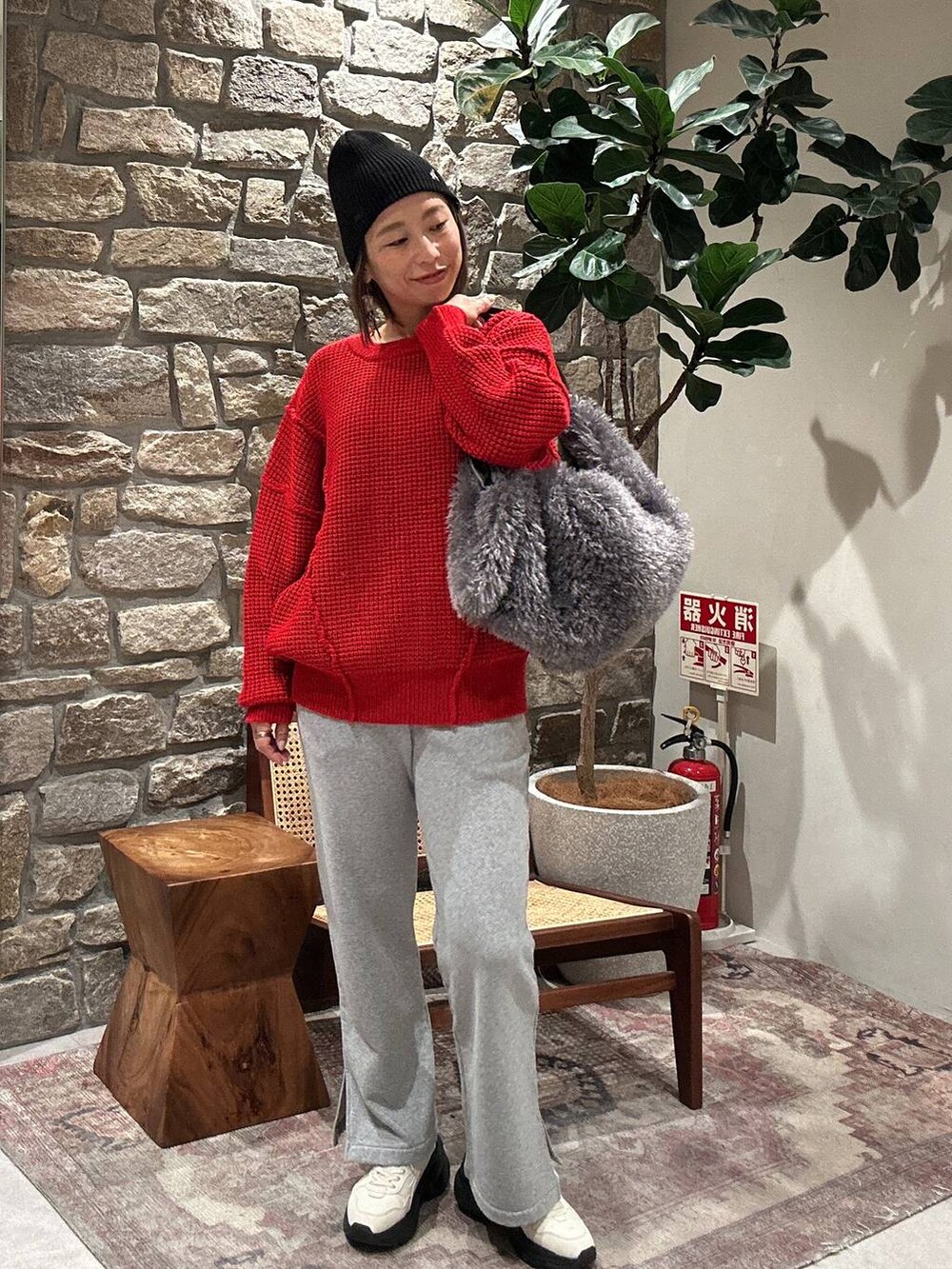 グレー系のスウェットパンツ、グレー系のトートバッグ、レッド系のニット/セーターを着用したレディースの冬コーディネートの3枚目の写真
