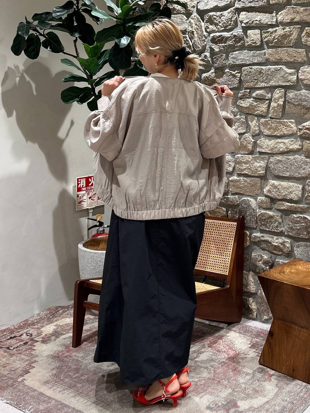 ベージュ系のブルゾン、レッド系のサンダル、ブラック系のジャンパースカートを着用したレディースの春コーディネートの2枚目の写真