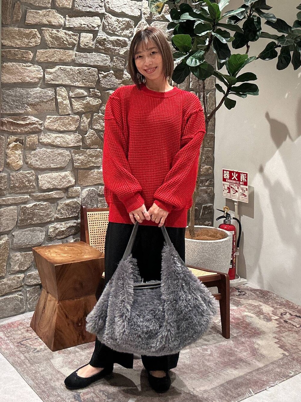 グレー系のトートバッグ、レッド系のニット/セーター、ブラック系のその他パンツを着用したレディースの冬コーディネートの2枚目の写真