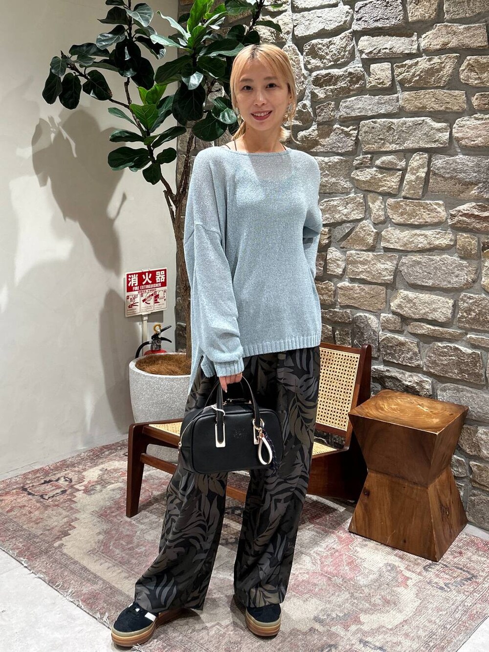 ブラック系のキャミソール、ブラック系のショルダーバッグ、ブルー系のニット/セーターを着用したレディースの春コーディネートの3枚目の写真