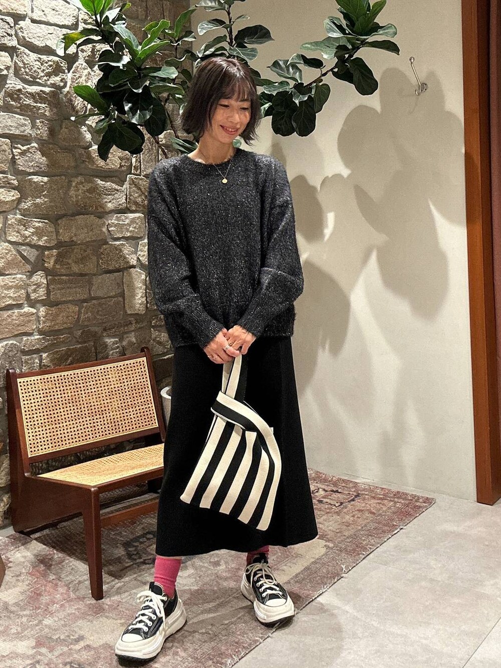 ブラック系のスカート、ブラック系のニット/セーター、ベージュ系のエコバッグ/サブバッグを着用したレディースの秋コーディネートの3枚目の写真