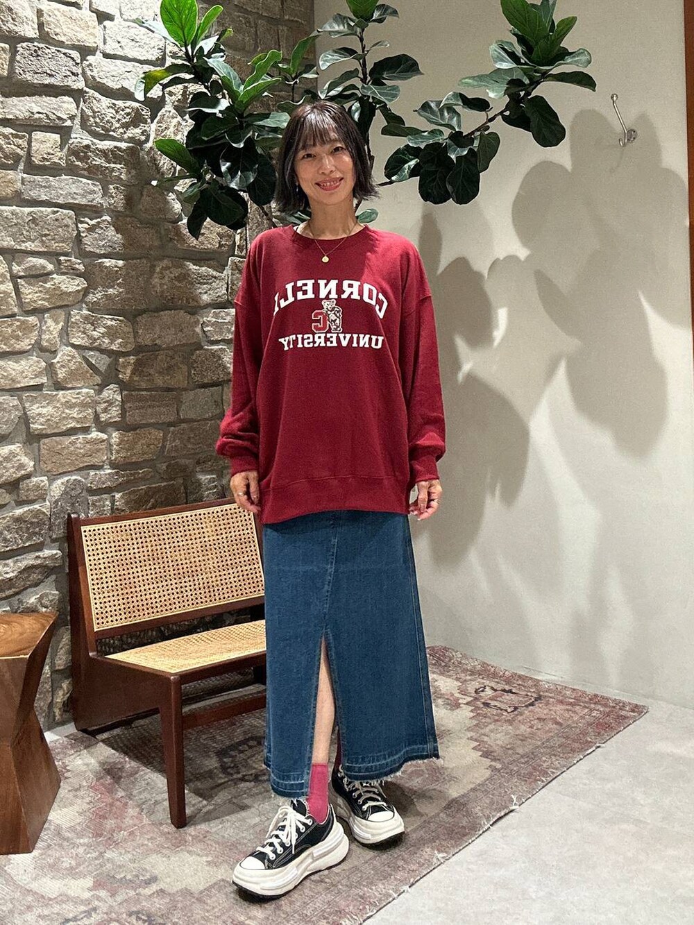 ブルー系のデニムスカート、レッド系のスウェットを着用したレディースの秋コーディネートの3枚目の写真