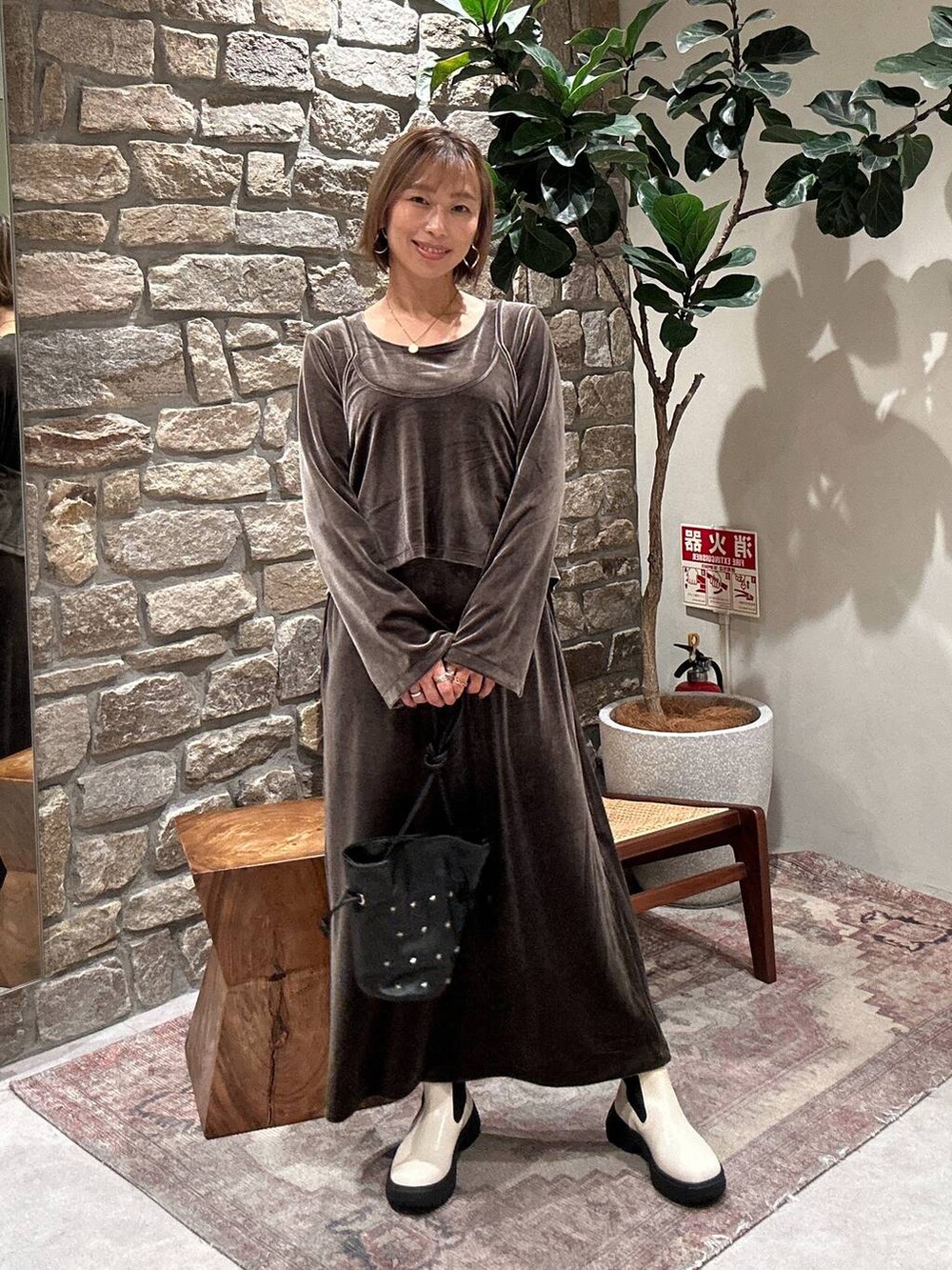 ブラック系のショルダーバッグ、ホワイト系のブーツ、グリーン系のワンピースを着用したレディースの秋コーディネートの3枚目の写真