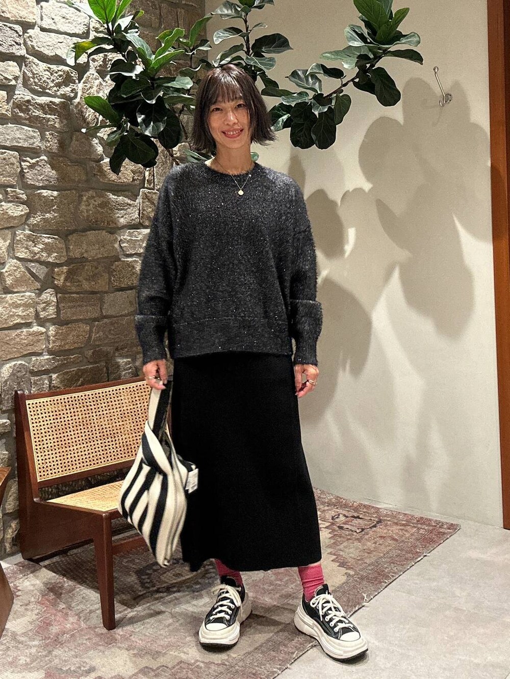 ブラック系のスカート、ブラック系のニット/セーター、ベージュ系のエコバッグ/サブバッグを着用したレディースの秋コーディネートの2枚目の写真