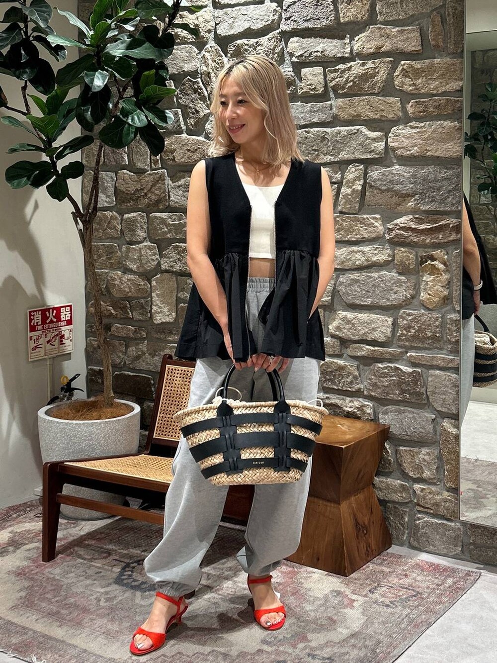 ブラック系のかごバッグ、レッド系のサンダル、グレー系のその他パンツを着用したレディースの夏コーディネートの2枚目の写真