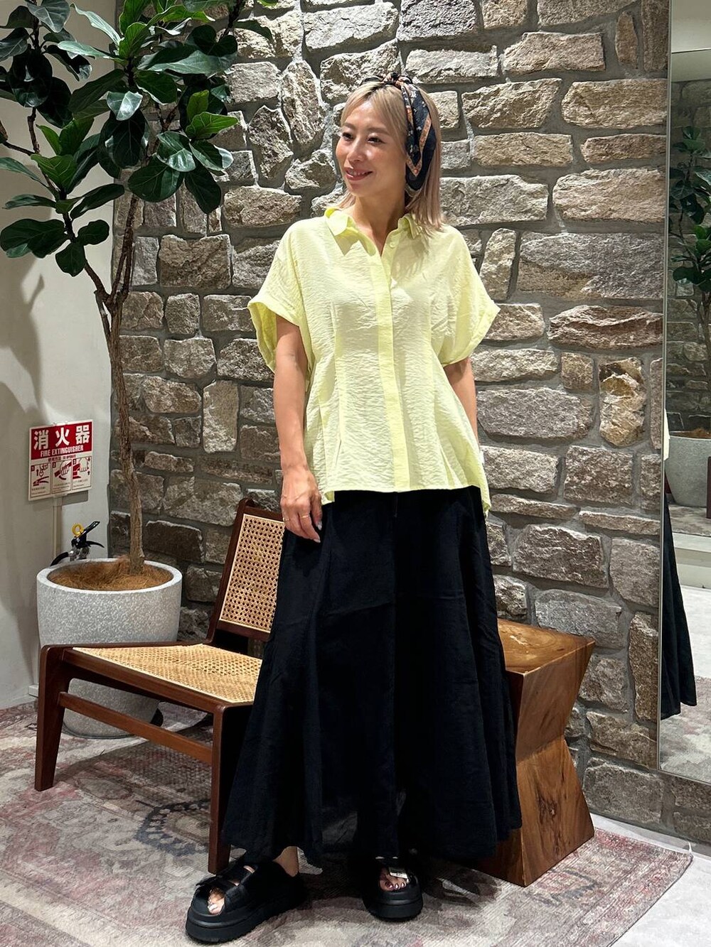 ブラック系のサンダル、ブラック系のスカート、イエロー系のシャツ/ブラウスを着用したレディースの夏コーディネートの2枚目の写真