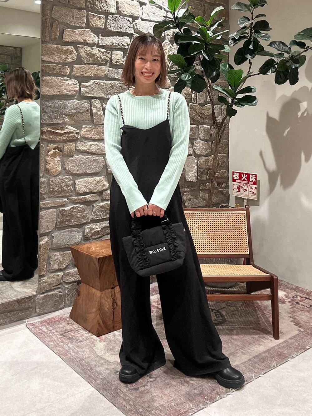 ブラック系のブーツ、グリーン系のニット/セーター、ブラック系のトートバッグを着用したレディースの冬コーディネートの3枚目の写真