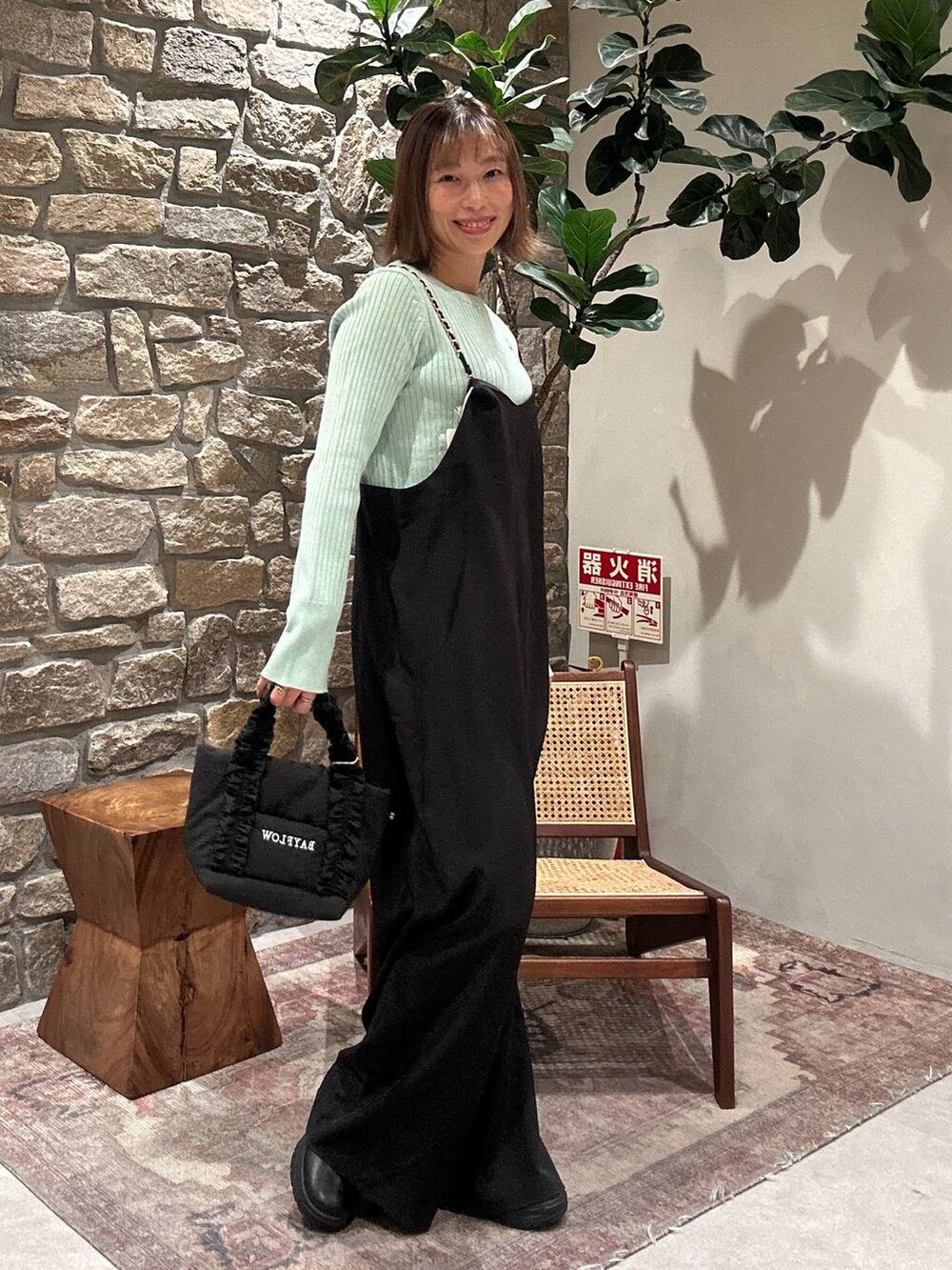 ブラック系のブーツ、グリーン系のニット/セーター、ブラック系のトートバッグを着用したレディースの冬コーディネートの2枚目の写真