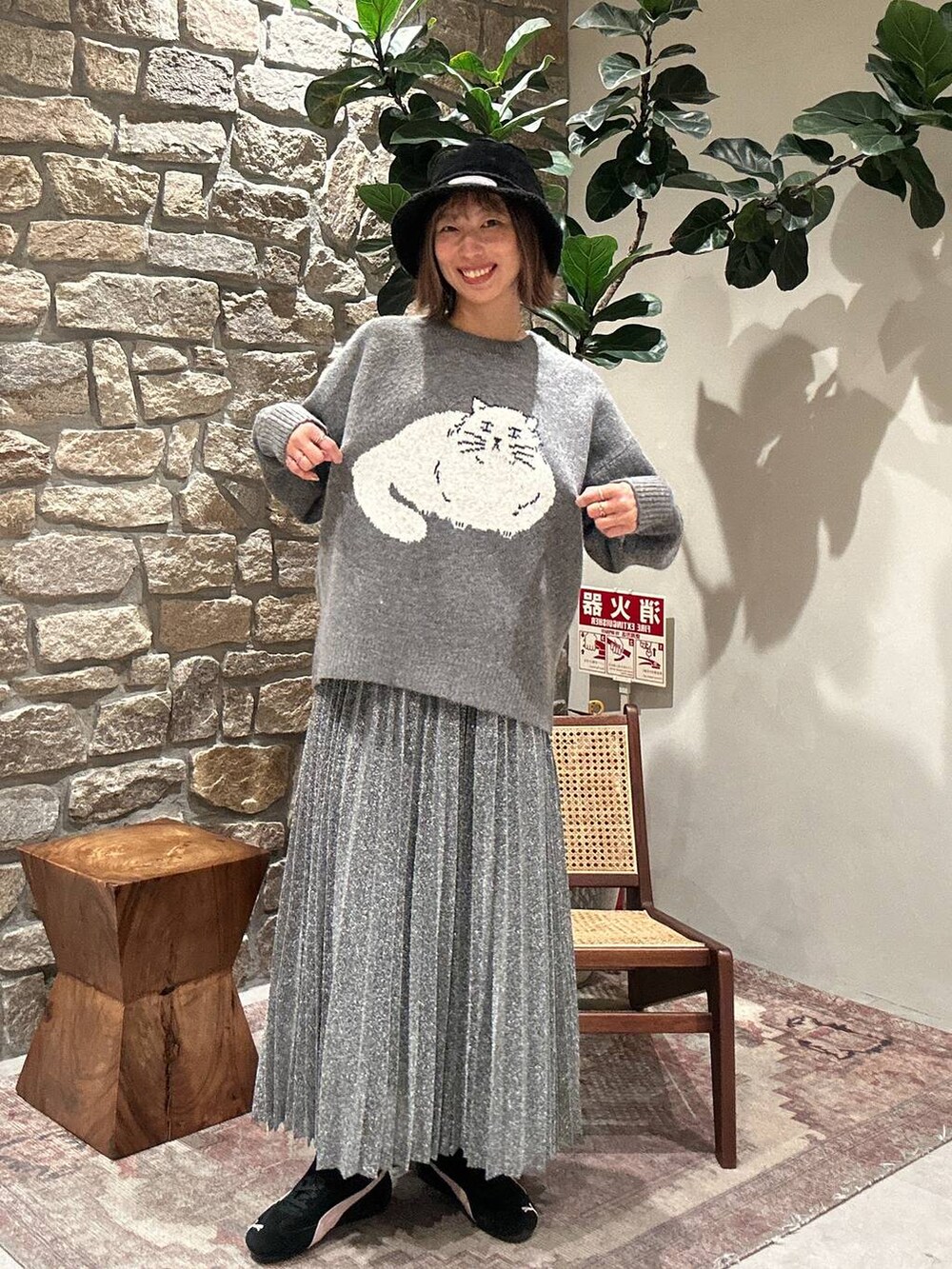 シルバー系のスカート、グレー系のニット/セーター、ブラック系のハットを着用したレディースの冬コーディネートの3枚目の写真