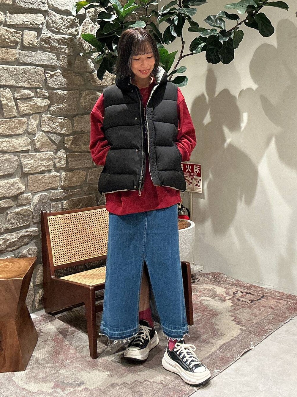 ブルー系のデニムスカート、ブラック系のベスト、レッド系のスウェットを着用したレディースの秋コーディネートの2枚目の写真
