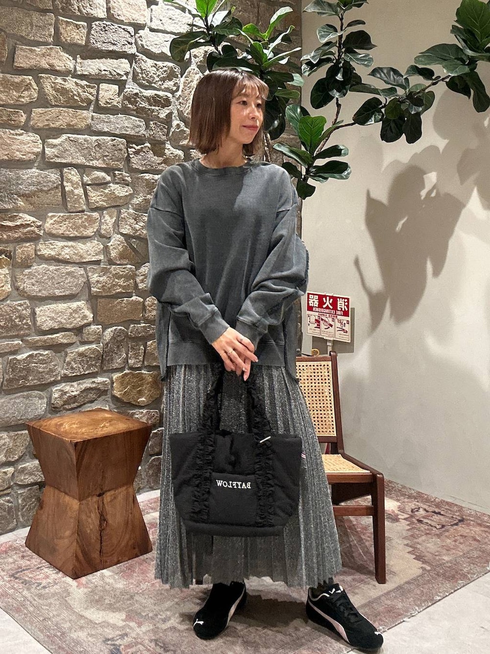 シルバー系のスカート、ブラック系のトートバッグ、グレー系のスウェットを着用したレディースの冬コーディネートの3枚目の写真