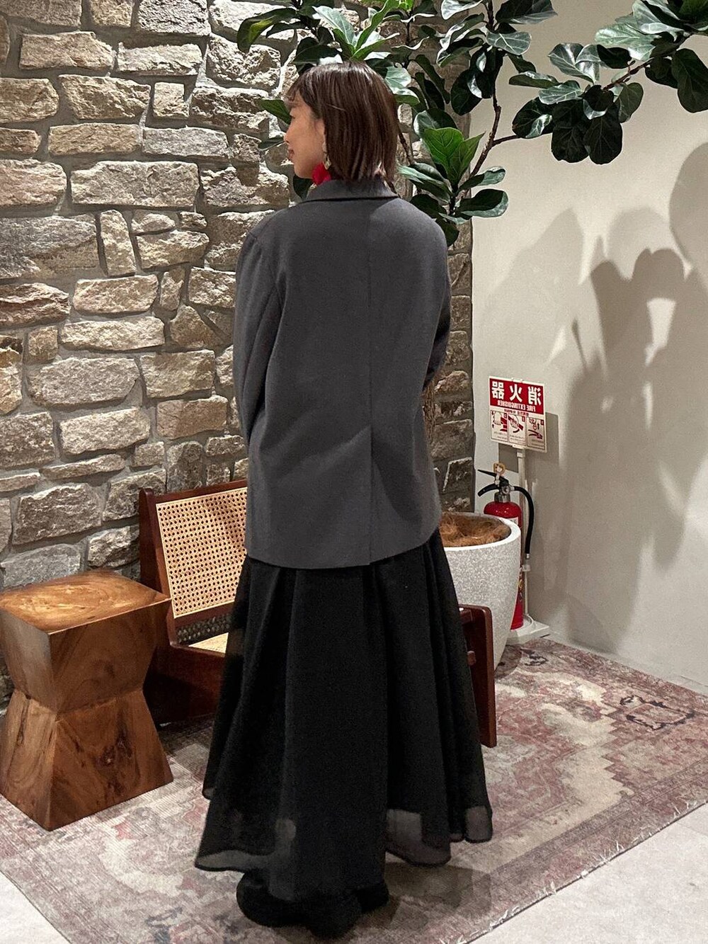 レッド系のニット/セーター、ブラック系のショルダーバッグ、ブラック系のブーツを着用したレディースの秋コーディネートの3枚目の写真