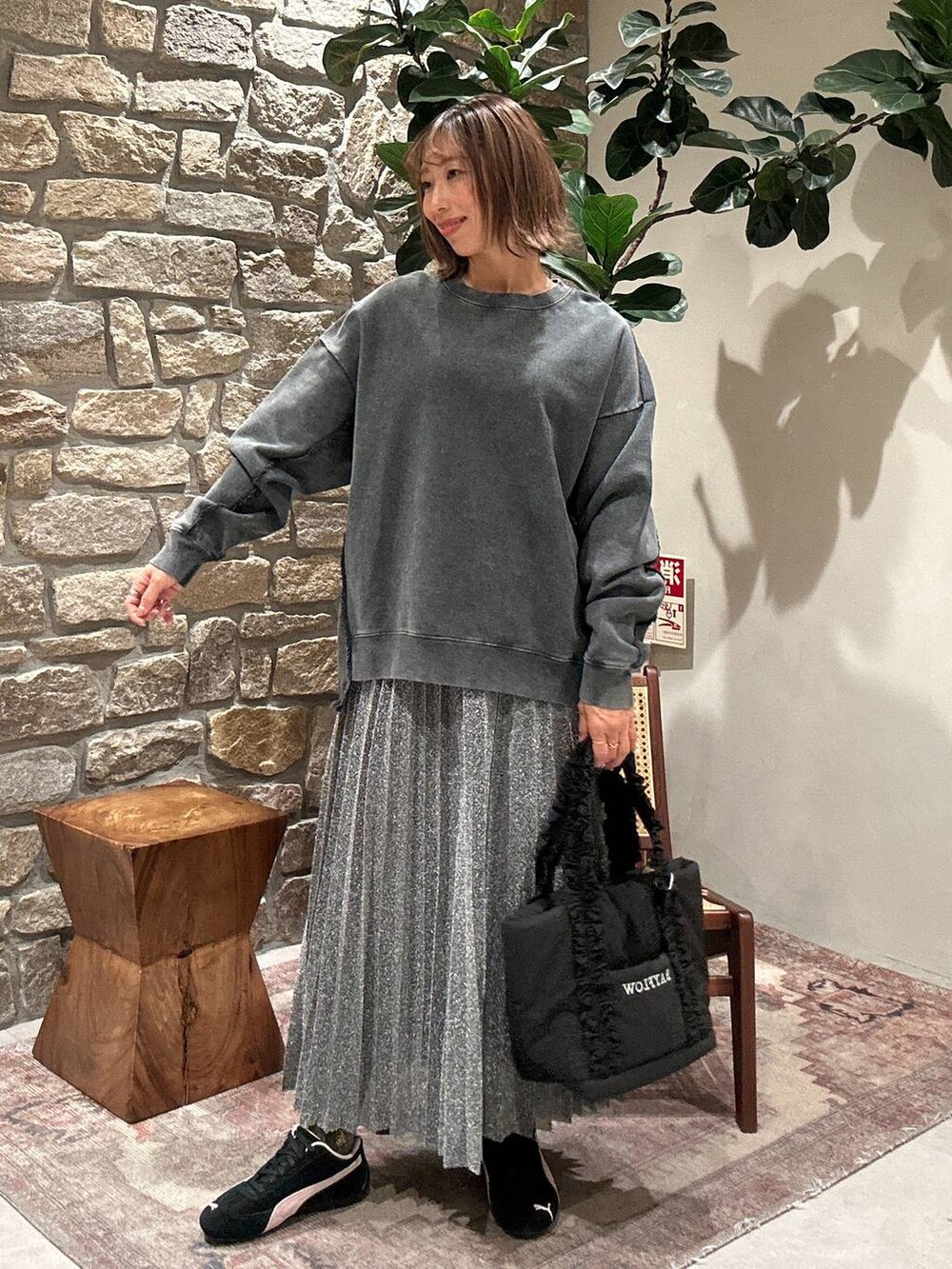 シルバー系のスカート、ブラック系のトートバッグ、グレー系のスウェットを着用したレディースの冬コーディネートの2枚目の写真