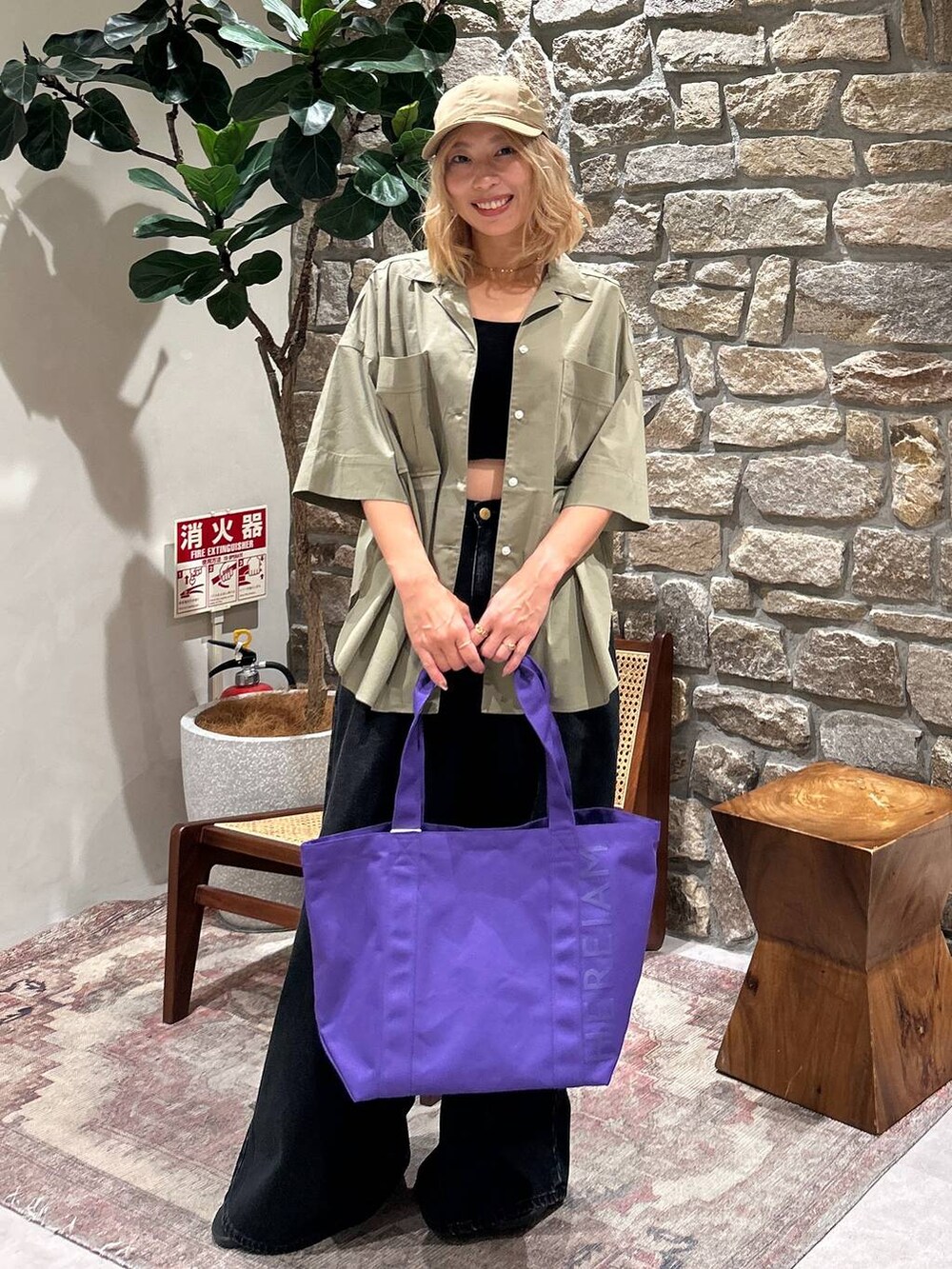 パープル系のトートバッグ、グリーン系のシャツ/ブラウス、ベージュ系のキャップを着用したレディースの春コーディネートの3枚目の写真