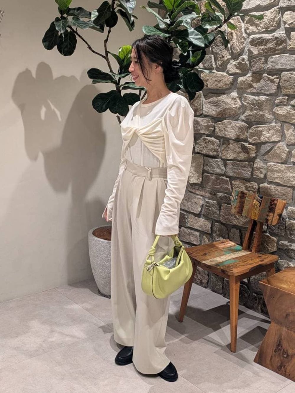 ベージュ系のスラックス、グリーン系のハンドバッグ、ホワイト系のTシャツ/カットソーを着用したレディースの春コーディネートの2枚目の写真