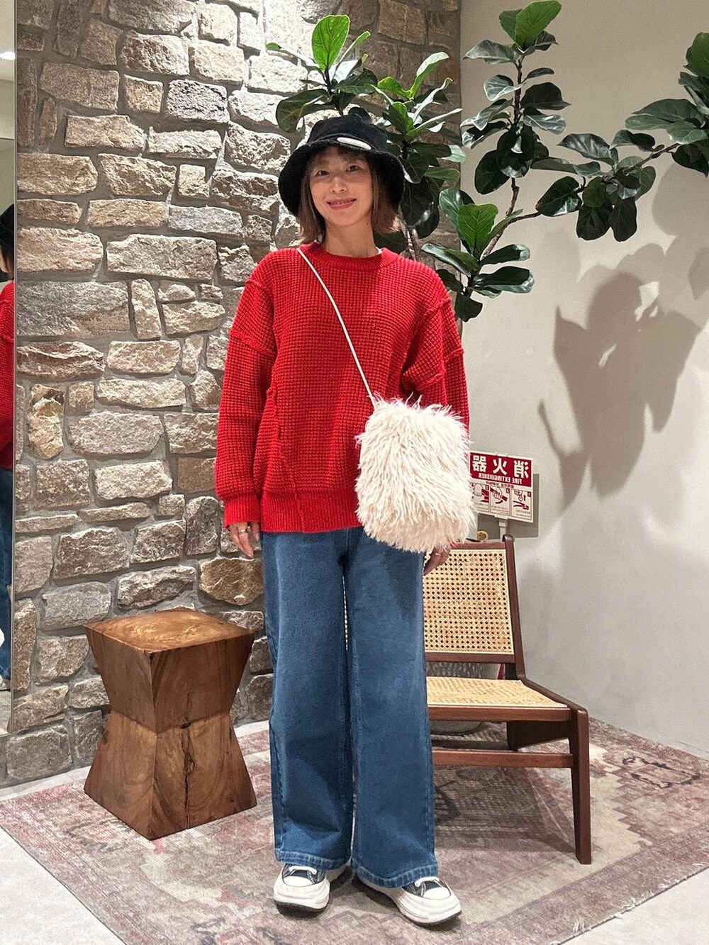 レッド系のニット/セーター、ブルー系のデニムパンツ、ブラック系のハットを着用したレディースの冬コーディネートの2枚目の写真