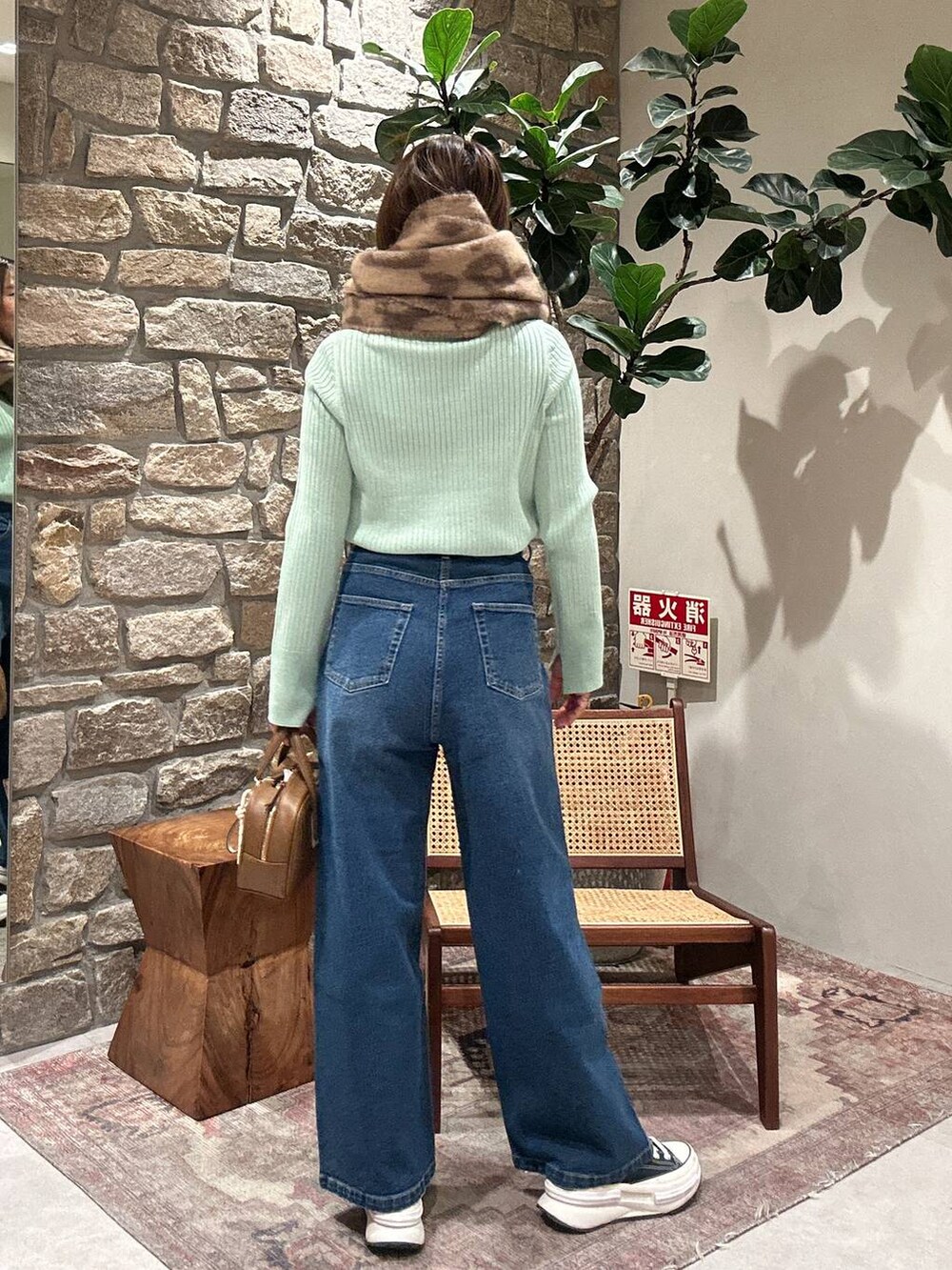 グリーン系のニット/セーター、イエロー系のショルダーバッグ、ブルー系のデニムパンツを着用したレディースの冬コーディネートの2枚目の写真