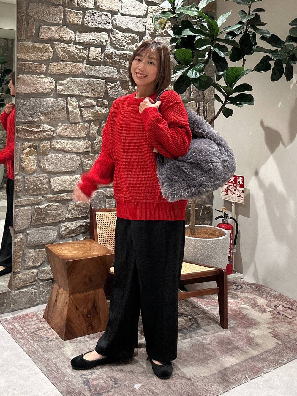 グレー系のトートバッグ、レッド系のニット/セーター、ブラック系のその他パンツを着用したレディースの冬コーディネートの3枚目の写真