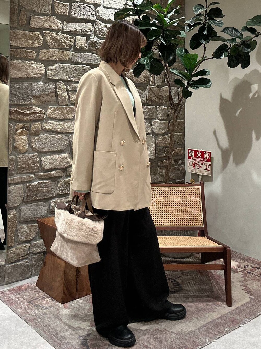 ブラック系のブーツ、グリーン系のニット/セーター、ベージュ系のテーラードジャケットを着用したレディースの冬コーディネートの2枚目の写真