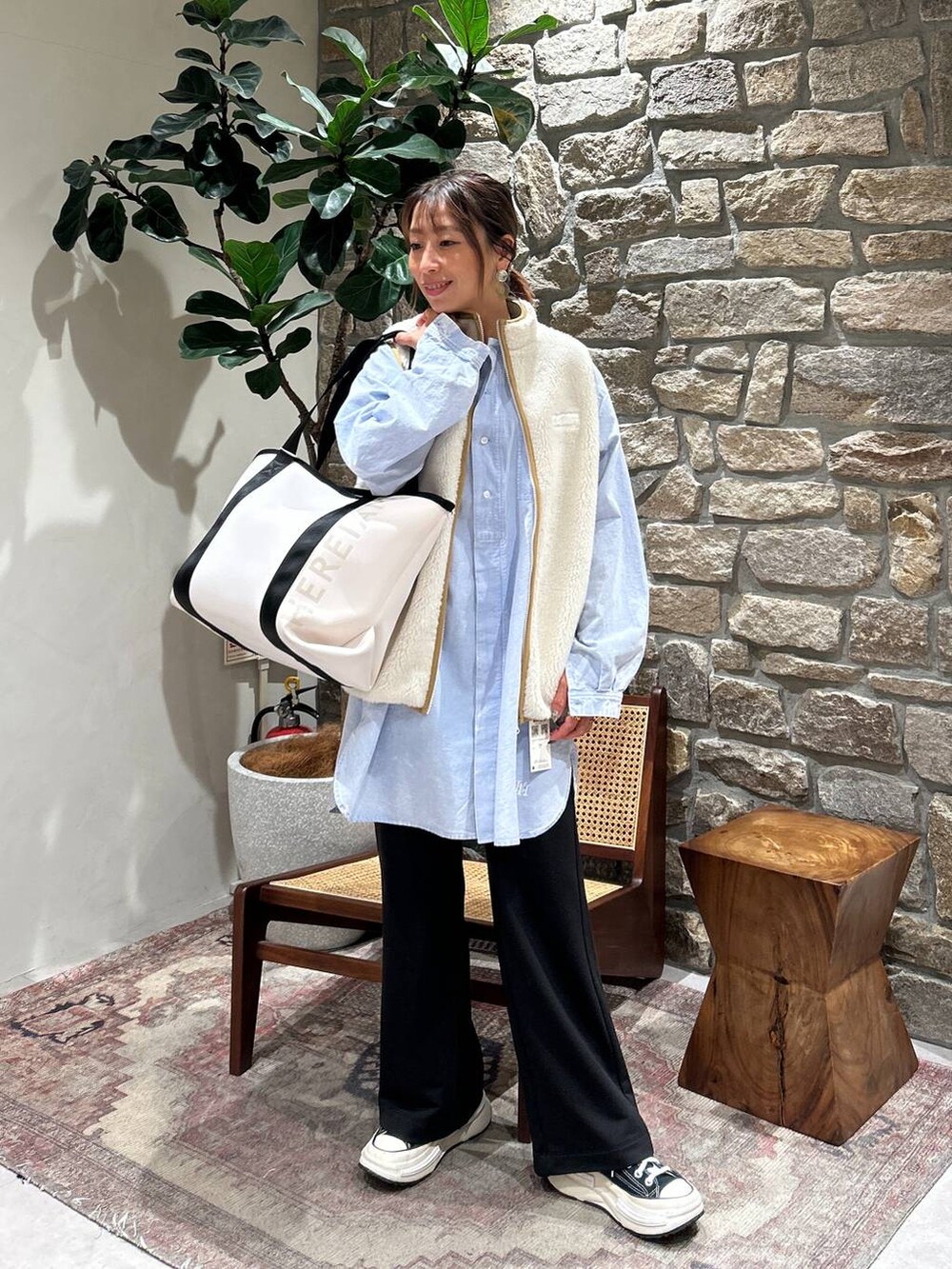 ホワイト系のダウンベスト、ブルー系のシャツ/ブラウス、ベージュ系のトートバッグを着用したレディースの冬コーディネートの2枚目の写真