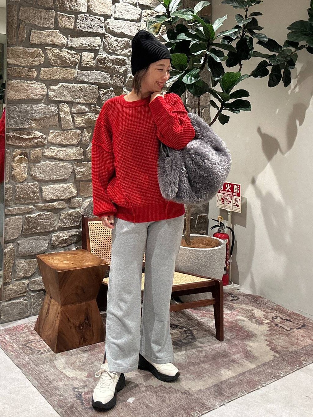 グレー系のスウェットパンツ、グレー系のトートバッグ、レッド系のニット/セーターを着用したレディースの冬コーディネートの2枚目の写真