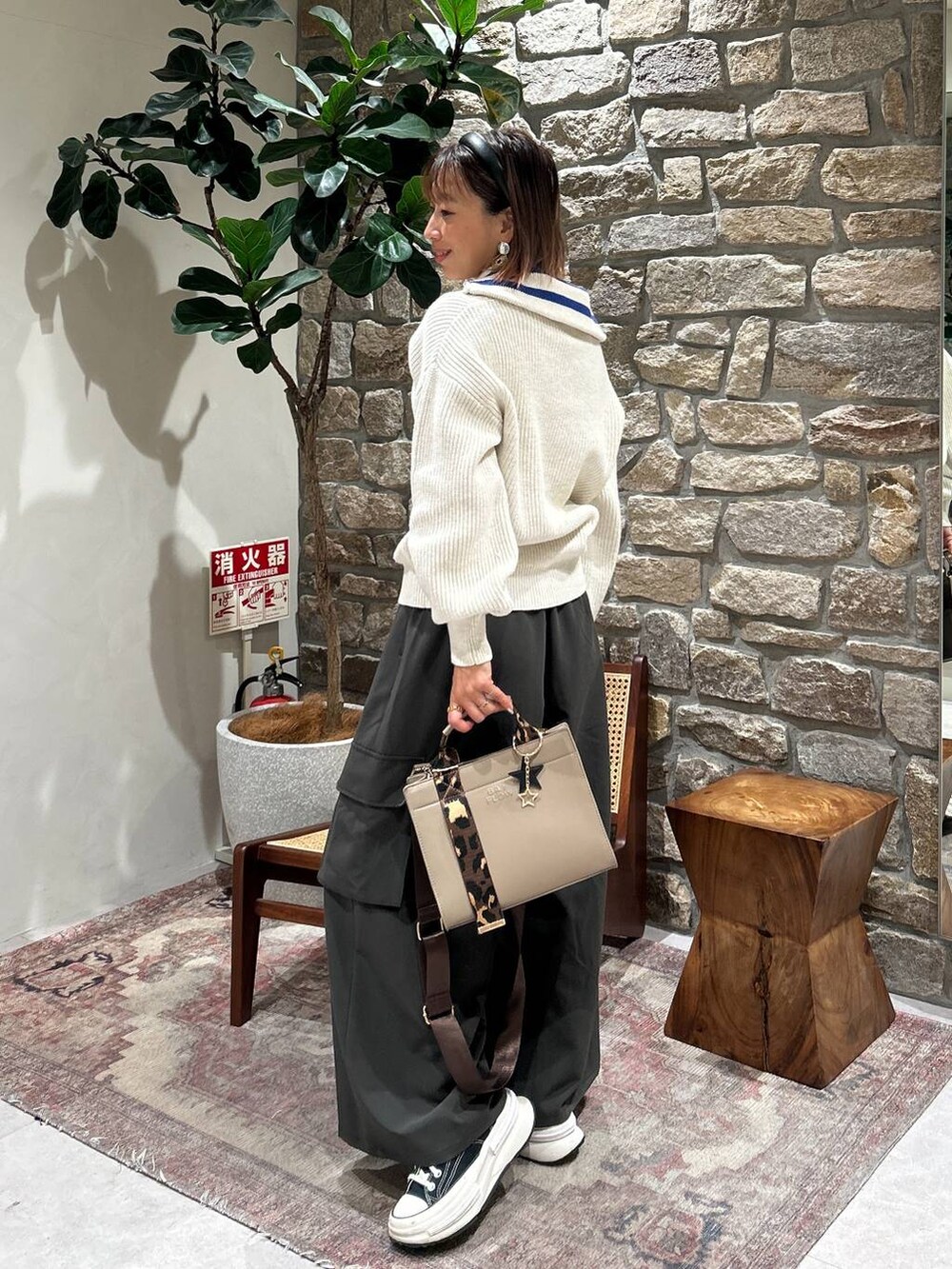 ベージュ系のハンドバッグ、グレー系のその他パンツ、ホワイト系のニット/セーターを着用したレディースの冬コーディネートの2枚目の写真