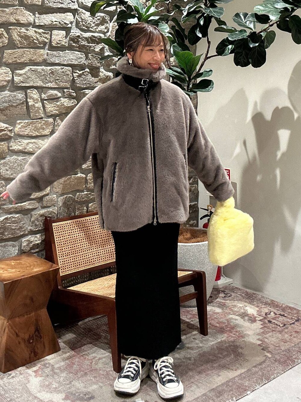 ブラック系のスカート、イエロー系のハンドバッグ、ベージュ系のブルゾンを着用したレディースの秋コーディネートの3枚目の写真