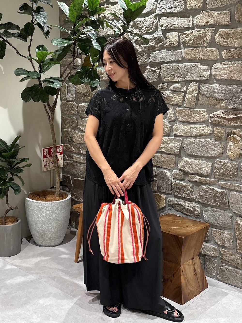 ブラック系のシャツ/ブラウス、ピンク系のハンドバッグ、ブラック系のサンダルを着用したレディースの夏コーディネートの2枚目の写真
