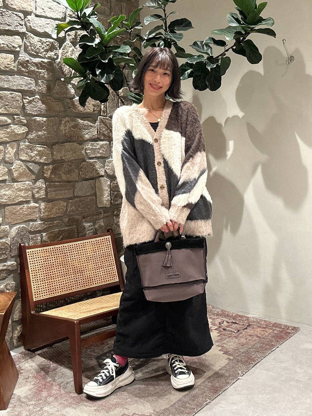 ブラック系のスカート、ブラウン系のカーディガン/ボレロ、グレー系のショルダーバッグを着用したレディースの秋コーディネートの2枚目の写真